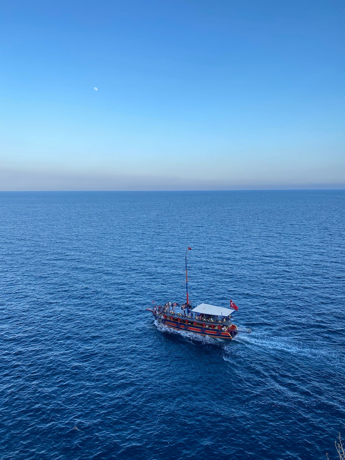 Traditional wooden Turkish passenger boat under way on open blue sea with a deck full of passengers