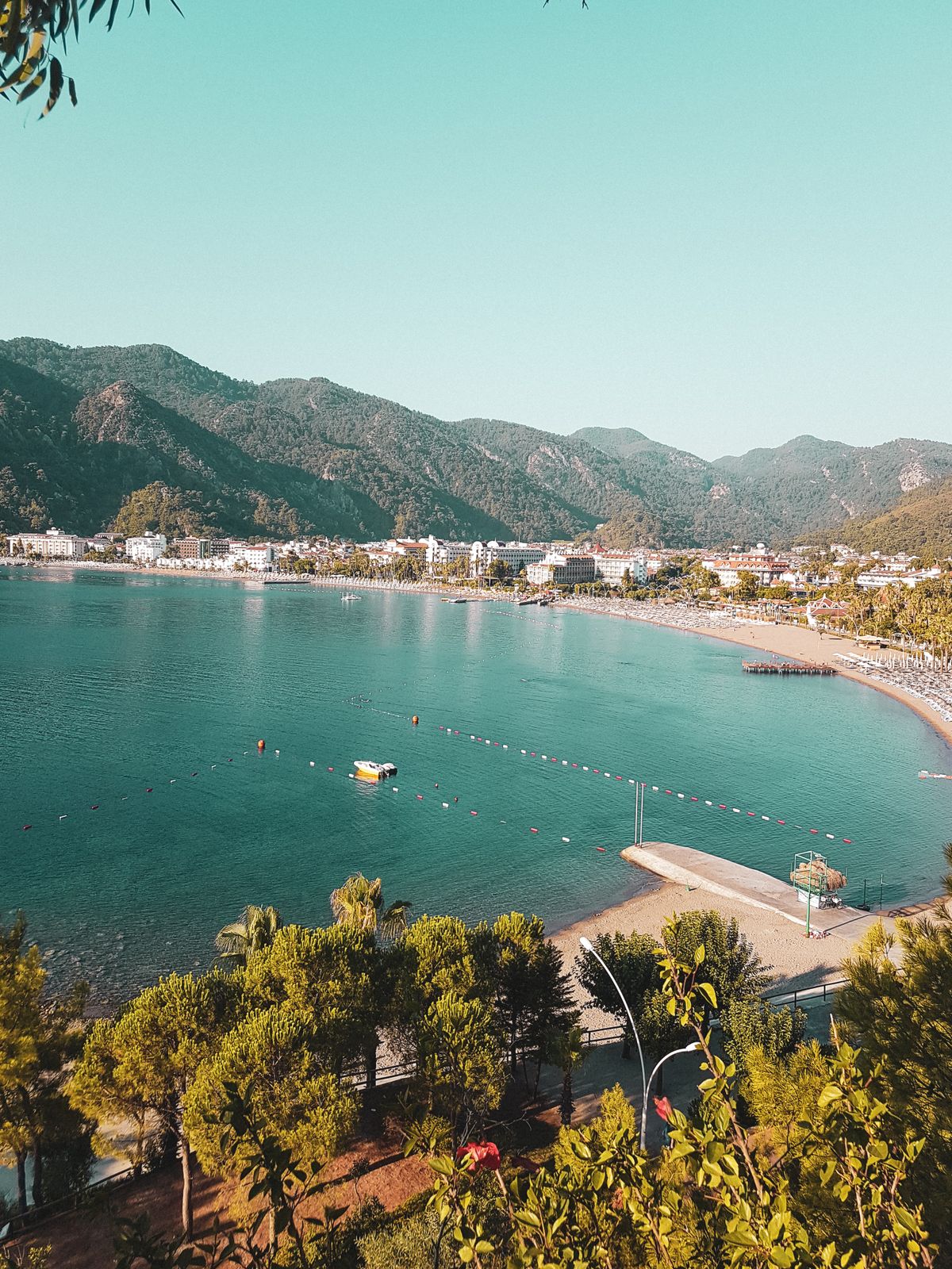 İçmeler bay with steep pine-covered mountains rising directly behind the shoreline and calm water in the foreground